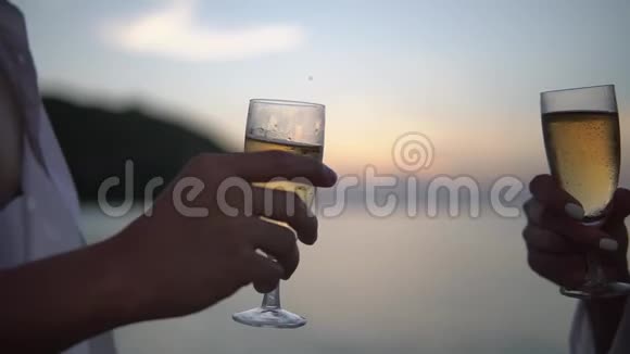 一对夫妇手里拿着一杯香槟伴着夕阳西下的慢动作视频的预览图