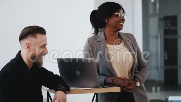 年轻的非洲女人和穿着正式衣服的中年欧洲男人在现代办公室研讨会上笑着视频的预览图