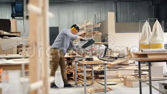 使用电锯的男性工人在木车间锯木单独工作视频的预览图