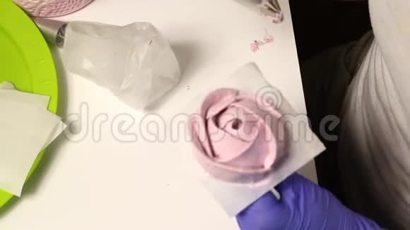 女人形成棉花糖玫瑰使用特殊的支架和糕点袋从上面看视频的预览图