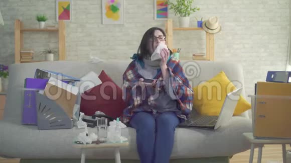商务女性工作狂病打喷嚏坐在沙发上在家工作视频的预览图