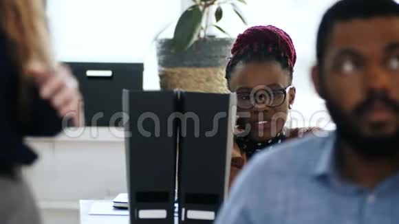 年轻时强调戴眼镜的非洲女公司经理在多民族现代办公室的餐桌上打电话视频的预览图