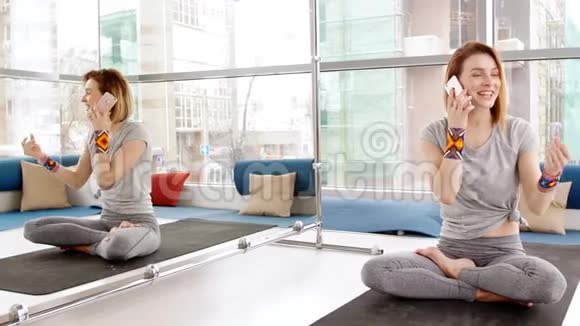 快乐的年轻女子在瑜伽室的智能手机上聊天视频的预览图