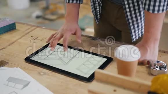 男木匠看平板电脑上家具的技术图纸视频的预览图