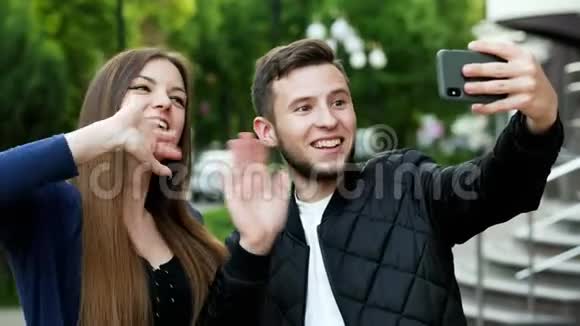 快乐的年轻夫妇在街上通过手机与朋友视频聊天视频的预览图