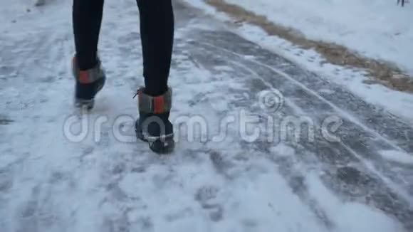 穿着黑色靴子在冬季小径上跳舞的女性腿覆盖着雪后景色穿着冬鞋跳舞的年轻女子的腿视频的预览图