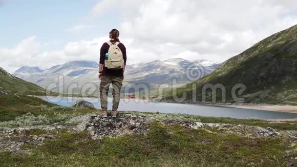 女子背包客站在一个山湖前欣赏风景视频的预览图