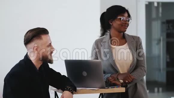 年轻的非洲商业女性戴着眼镜站在中年商人附近微笑着健康的现代办公室视频的预览图