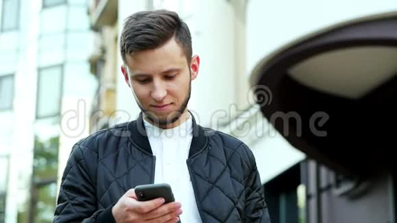 年轻的商人拿着现代手机男人正在打短信聊天视频的预览图