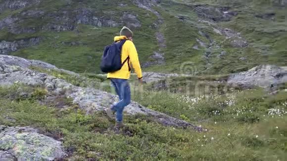 穿着一件亮黄色夹克的女子背包客在山上散步视频的预览图