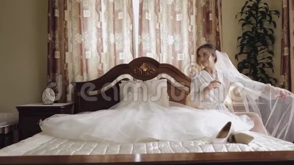 美丽可爱的新娘身穿睡衣头纱坐着喝香槟视频的预览图