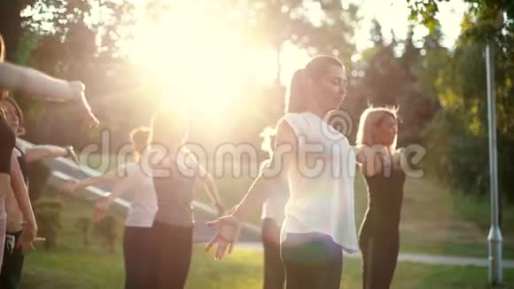 一群年轻女性在日出时一起在公园里练习瑜伽视频的预览图