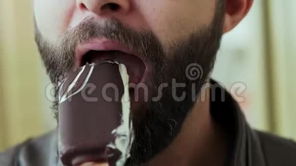 饥饿的大胡子男人吃巧克力冰淇淋的特写镜头视频的预览图