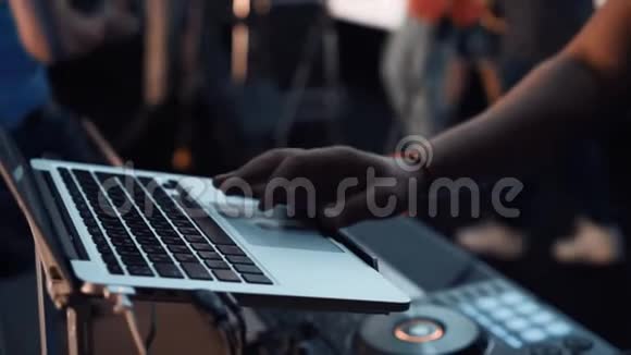 舞台音乐会前专业DJ遥控器的录像DJ把他的手放在笔记本电脑上准备视频的预览图