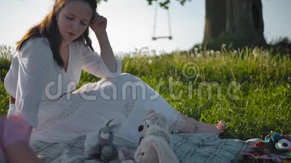 一位年轻的母亲和她的两个小女儿在一棵孤独的老橡树附近的空地上野餐视频的预览图