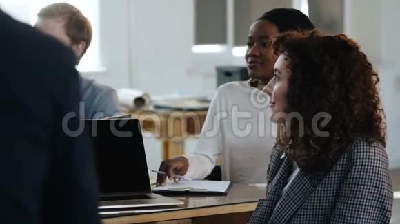 侧面观察两位女性公司同事非洲和高加索职业经理在现代办公室团队会议视频的预览图