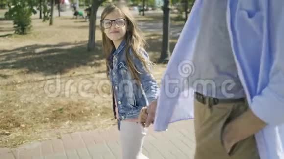 哥哥牵着妹妹的手在城市的背景下在公园里散步视频的预览图