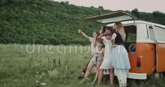 赛尔夫时代在田野的中间一群年轻的女士坐在一辆复古面包车的后面拍照视频的预览图