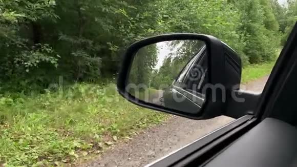 汽车在穿过绿色的夏林的道路上行驶道路被反射在侧镜中视频的预览图