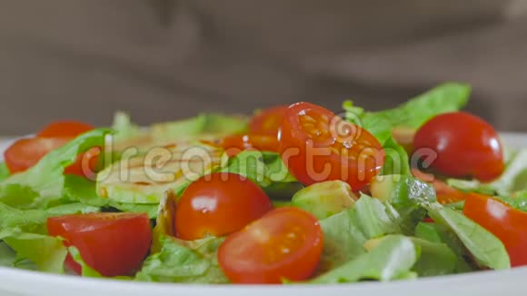 厨房里的一个男人准备了一份牛油果西葫芦和樱桃西红柿的沙拉并把大的开胃虾放在上面视频的预览图