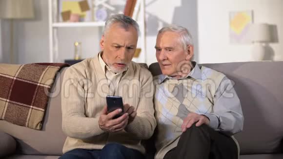 老年男性展示新智能手机老年朋友使用现代技术视频的预览图