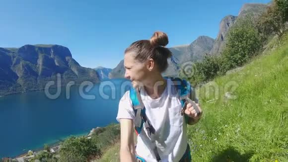年轻女子背包客在挪威峡湾背景下自拍视频的预览图