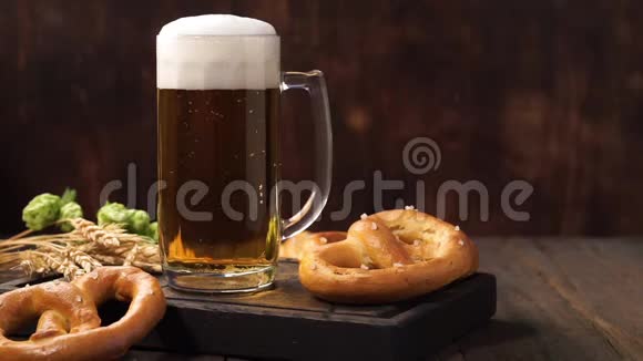 新鲜的泡沫啤酒在一个玻璃杯在一个黑暗的木桌上视频的预览图