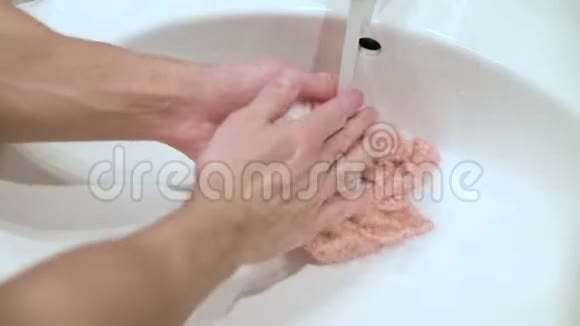 一个人用双手水槽里洗了一件儿童衬衫视频的预览图