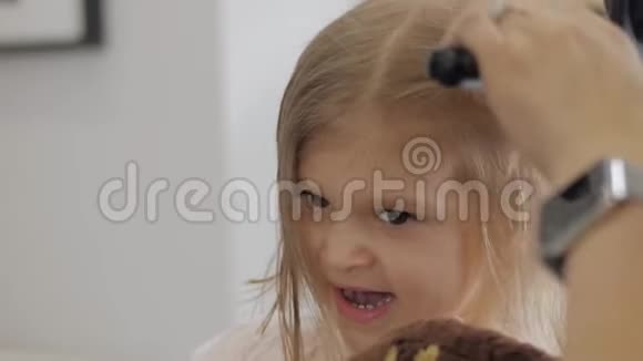 在美容院的金发小女孩理发师用吹风机擦干头发做造型视频的预览图