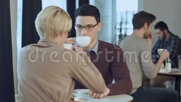 一对年轻夫妇在咖啡馆的窗户附近聊天喝咖啡视频的预览图