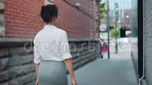 一幅快乐的年轻女士走着走着转过头看着镜头微笑的画像视频的预览图