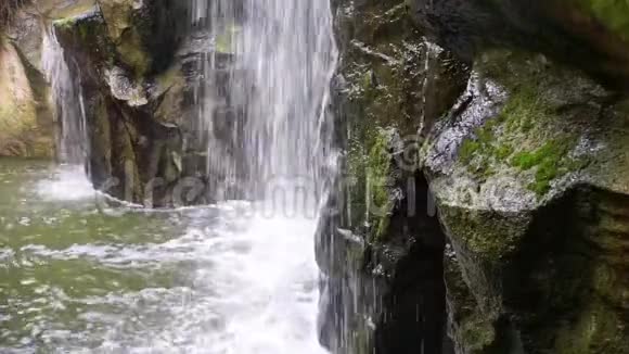 瀑布落于水中苔藓岩与流水特写自然背景视频的预览图