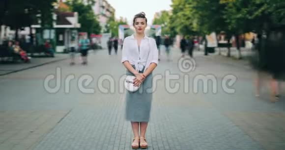 在繁忙的街道上站在市中心的有魅力的成年女性的时间流逝视频的预览图