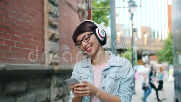 女孩在户外使用智能手机在耳机中听音乐的慢动作视频的预览图