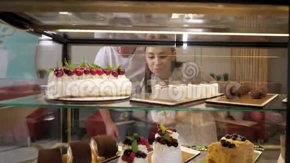 快乐的一对夫妇在玻璃橱窗里挑选美味的蛋糕视频的预览图