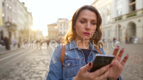 女人用智能手机走在老街上在日落时拍照慢动作视频的预览图