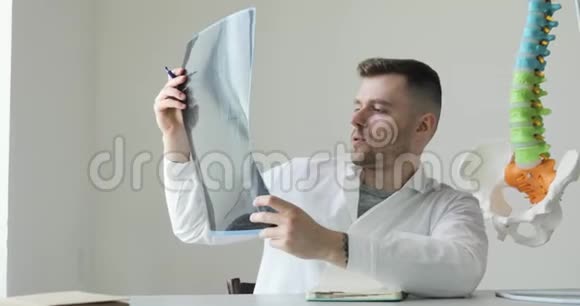 年轻医生外科医生的肖像正在观察x线图像并向病人解释疾病视频的预览图