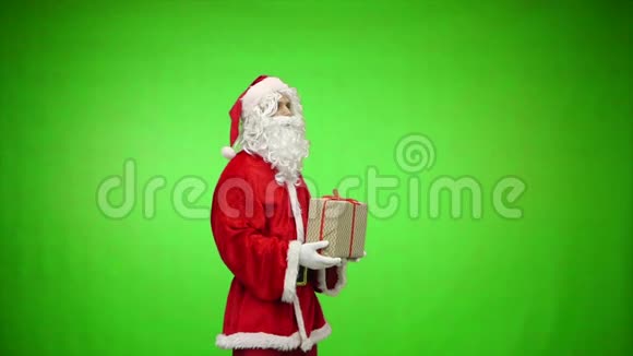 圣诞老人拿着两件绿色背景的圣诞礼物慢动作视频的预览图