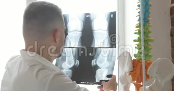 医生正在学习x光图像上的骨头坐在靠近窗户的地方后视视频的预览图