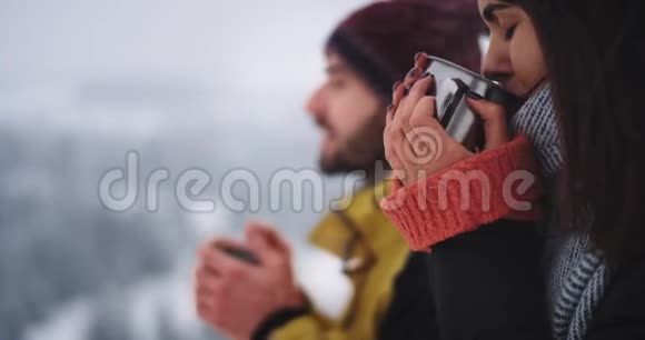 两位年轻游客的详细画像喝了一些热茶在山顶上有雪的令人惊叹的冬天视频的预览图