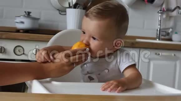 迷人的小男孩在厨房吃第一个食物桃子妈妈给孩子喂奶视频的预览图