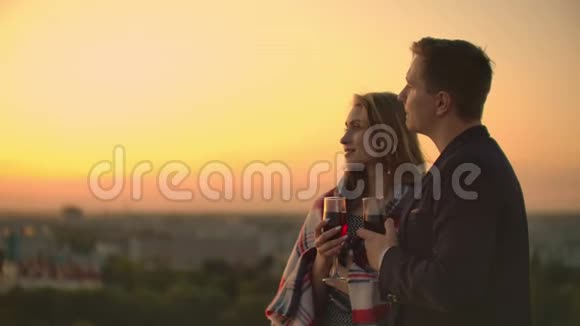 情人拥抱男女孩看日落酒站在楼顶慢镜头画面视频的预览图