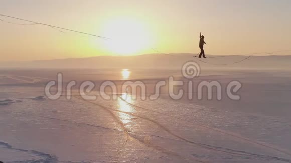 走钢丝的人正在一条绳子上平衡在冰冻湖上方的两块岩石之间视频的预览图
