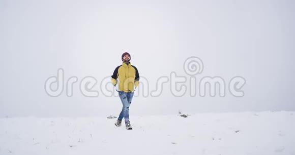 快乐而微笑的年轻游客走过田野中央的雪美丽的冬天在周围视频的预览图