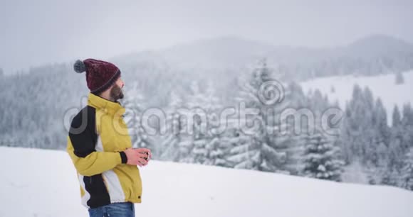 漂亮的游客在雪林中休息一下他喝了一杯热茶沉思着欣赏视频的预览图