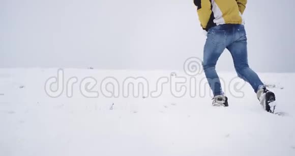 在大雪纷飞的一天里遛狗的人穿过雪地来到山顶外面的冬天是美丽的视频的预览图