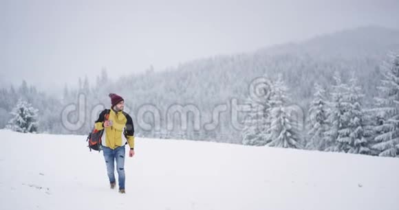 步行游客穿过雪域手捧一杯热茶在背景上获得温暖美丽的景观视频的预览图