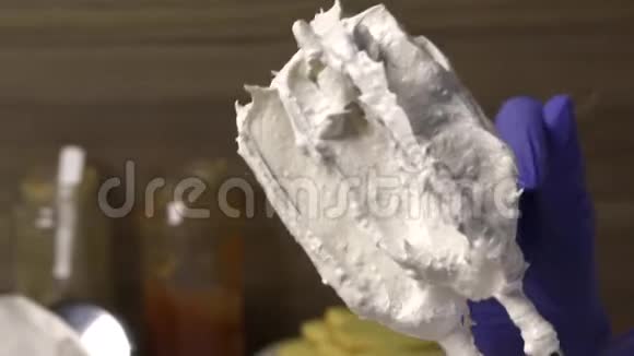 女人用棉花糖清洗搅拌机的搅拌器用勺子把它移开放在容器里视频的预览图