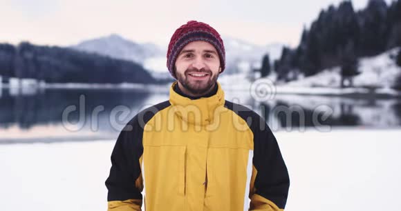 镜头前穿着橙色夹克的魅力男人的肖像笑容满面有人用他的雪球射击视频的预览图