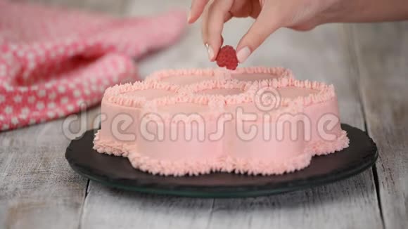 糕点厨师正在用新鲜的覆盆子装饰一个粉红色的花朵形状的蛋糕系列视频的预览图